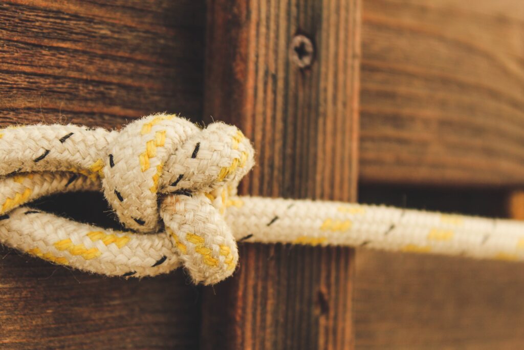 yellow paracord survival knot next to brown wood