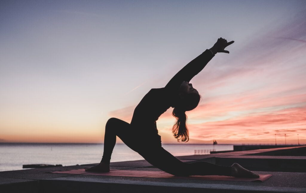 silhouette of a person doing yoga in front of a sunset